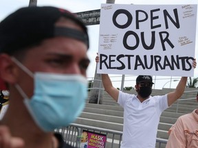 Alex Aguilar (centre), along with other restaurant owners, workers and supporters, gather to protest on July 10, 2020 in Miami.