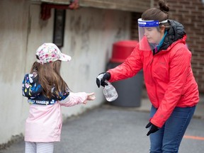 A student has her hands sanitized in the schoolyard, as schools outside the greater Montreal region begin to reopen their doors amid the coronavirus disease (COVID-19) outbreak, in Saint-Jean-sur-Richelieu, Quebec, Canada May 11, 2020.