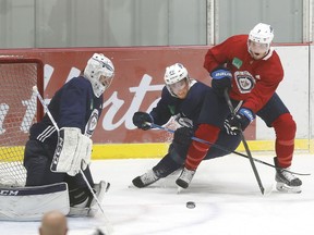 Winnipeg Jets center Cody Eakin (20) checks Winnipeg Jets defenseman Dmitry Kulikov (7) in front of Winnipeg Jets goaltender Connor Hellebuyck (37) during a NHL workout at Bell MTS Iceplex.