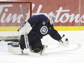 Winnipeg Jets goaltender Connor Hellebuyck (37) gloves the puck during a NHL workout at Bell MTS Iceplex.