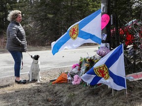 Denise Caume and her dog, Mimi, are seen in front of the makeshift memorial, made in the memory of a mass shooting in Portapique, Nova Scotia, April 23, 2020.