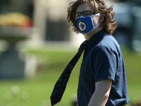 A man wearing a tie and a mask walks past the Manitoba Legislature on Thursday.
