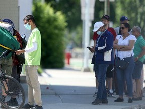 People wear masks while waiting to enter a bank in downtown Winnipeg on Friday.