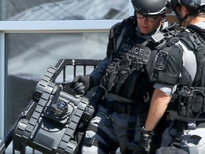 Members of the Winnipeg Police Service's Tactical Support Team remove their tactical support robot, named Kevin, from a home on Selkirk Avenue on Friday.