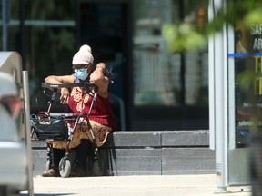 A woman wears a mask while seated on an otherwise empty Winnipeg street on Saturday.