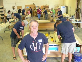 Sleep in Heavenly Peace (SHP) Winnipeg Chapter President Jim Thiessen (foreground) stands in front as volunteers work to put together wooden bed frames on Saturday.