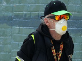 A man wears a mask while walking along a street in Winnipeg on Saturday.