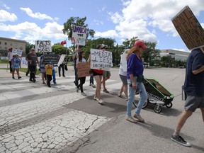 Protestors leave the Manitoba Legislative Building en route to the Forks for a March to Unmask event on Sunday, July 19.