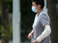 A person walks along Ellice Avenue, while wearing a mask, in Winnipeg on Tuesday.