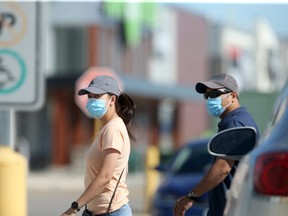 People walking through a parking lot, wearing masks, in Winnipeg. Tuesday, July 28/2020.
