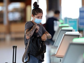 A woman prepares to check in at Winnipeg international airport on Monday. Masks will be mandatory in public areas of the airport terminal for passengers, visitors and employees beginning Wednesday.