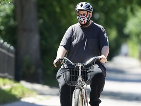 A man wearing a mask cycles down a backlane in the Wolseley area of Winnipeg on Monday.