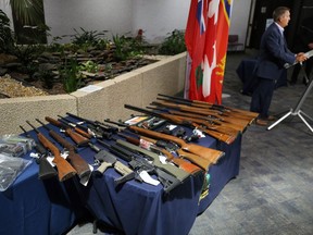 Some of the firearms seized by RCMP crime reduction teams are displayed as Justice Minister Cliff Cullen speaks during a press conference at 'D' Division headquarters in Winnipeg on Monday, July 27, 2020.