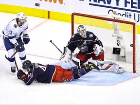 Vladislav Gavrikov and Joonas Korpisalo, right, of the Columbus Blue Jackets defend the goal against Brayden Point, left, of the Tampa Bay Lightning during the third period in Game 4 of the Eastern Conference First Round during the 2020 NHL Stanley Cup Playoffs at Scotiabank Arena on Aug. 17, 2020 in Toronto.