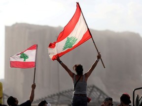 Demonstrators wave Lebanese flags during protests near the site of a blast at Beirut's port area, Lebanon August 11, 2020.