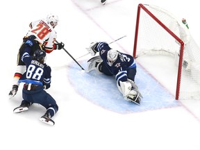 Elias Lindholm of the Calgary Flames scores on Winnipeg Jets goaltender Connor Hellebuyck  during Game 3 of their Western Conference play-in series on Tuesday.