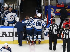 Jets forward Mark Scheifele is helped off of the ice by Nathan Beaulieu after a hard hit against the Calgary Flames in Game One of their playoff series last night. Getty Images