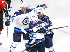 Nikolaj Ehlers (27) of the Winnipeg Jets is congratulated by teammates Cody Eakin (20) and Kyle Connor (81) after Ehlers scored in the third period against the Calgary Flames. This goal was Ehlers' first NHL playoff goal.