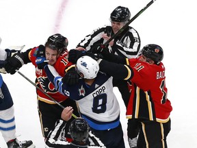 On ice officials try to break up a scuffle by Andrew Copp (9) of the Winnipeg Jets as he shoves Matthew Tkachuk (19) of the Calgary Flames as teammate Mikael Backlund (11) defends during a stop in play in the third period during Game Two of the Western Conference Qualification Round prior to the 2020 NHL Stanley Cup Playoffs at Rogers Place on August 3, 2020 in Edmonton, Alberta.