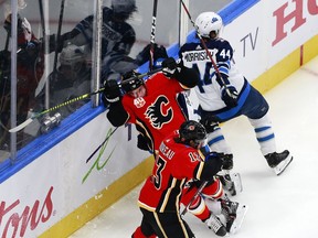 Johnny Gaudreau (13)  and Elias Lindholm (28) of the Calgary Flames battle with Josh Morrissey (44) of the Winnipeg Jets in Game One of the Western Conference Qualification Round prior to the 2020 NHL Stanley Cup Playoffs at Rogers Place on August 01, 2020 in Edmonton, Alberta. (Photo by Jeff Vinnick/Getty Images)