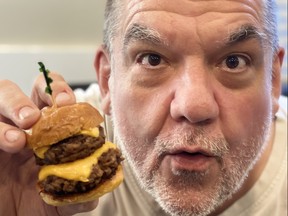 Hal Anderson holds up a mini double cheeseburger at the Pony Corral restaurant on Nairn in Winnipeg.