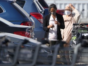 Two people wear masks while in the parking lot of a grocery store in Winnipeg on Friday.