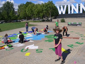 Organizer Jeannette Pantin (foreground) stands in front of group from the Greenpeace Winnipeg volunteer group who were painting a street mural to demand a green and just recovery for all in front the Winnipeg sign at The Forks on Saturday.