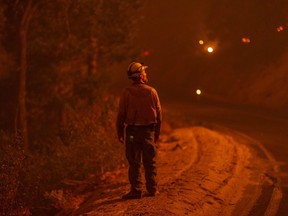 A firefighter keeps watch as flames advance along the Western Divide Highway during the SQF Complex Fire on September 14, 2020 near Camp Nelson, California.