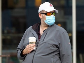 A man wearing a mask waits at a bus stop in Winnipeg, Sunday, Sept. 20, 2020.