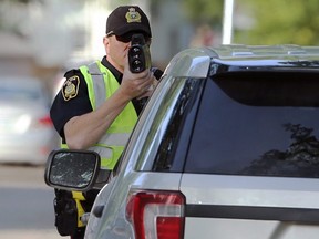 A police officer checks the speed of drivers in a school zone near Grosvenor School on Grosvenor Avenue in Winnipeg on the first days students returned on Tues., Sept. 8, 2020. Kevin King/Winnipeg Sun/Postmedia Network