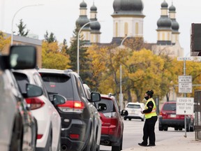 A woman conducts screening for the COVID-19 drive-through testing site in Winnipeg on Wed., Sept. 23, 2020. By mid-morning, there were 200 vehicles backed up with the expected wait time stretching into the lunch hour, the woman said. Kevin King/Winnipeg Sun/Postmedia Network