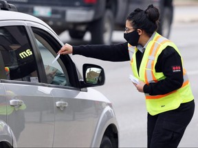 A woman conducts screening for the COVID-19 drive-through testing site in Winnipeg on Wed., Sept. 23, 2020. By mid-morning, there were 200 vehicles backed up with the expected wait time stretching into the lunch hour, the woman said. Kevin King/Winnipeg Sun/Postmedia Network