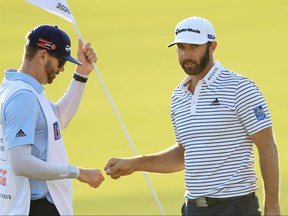 Dustin Johnson of the United States bumps fists with his caddie and brother Austin Johnson on the 18th green during the third round of the Tour Championship at East Lake Golf Club on Sept. 6, 2020 in Atlanta, Ga.