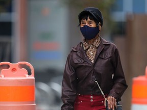 A woman wearing a mask walks through an area under construction on Hargrave Street in Winnipeg on Sunday.