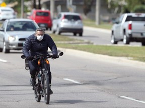 A man wearing a mask rides a bicycle on Grant Avenue in Winnipeg on Tues., Sept. 8, 2020. Kevin King/Winnipeg Sun/Postmedia Network