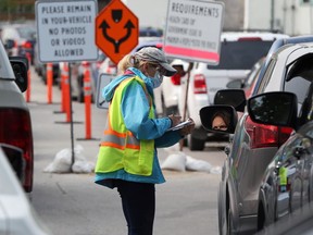A Winnipeg Regional Health Authority employee conducts screening in the parking lot of the drive-thru COVID-19 community testing site on Main Street in Winnipeg on Mon., Sept. 14, 2020. Kevin King/Winnipeg Sun/Postmedia Network