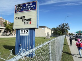 People wearing backpacks pass John Pritchard School on Henderson Highway in Winnipeg on Wednesday, Sept. 16
