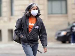 A woman wearing a mask crosses Portage Avenue in Winnipeg.