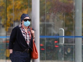 A woman wearing a mask waits for a bus in the Osborne Village area of Winnipeg on Thursday, Sept. 24, 2020.