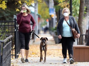 Two women wearing masks walk on Corydon Avenue in Winnipeg on Sunday.