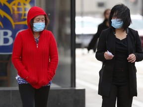 Two women wearing masks cross Portage Avenue in Winnipeg on Tues., Sept. 29, 2020. Kevin King/Winnipeg Sun/Postmedia Network