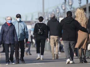 People wear face masks as they walk along the promenade in the Old Port of Montreal, Monday, Oct. 12, 2020, as the COVID-19 pandemic continues in Canada and around the world.