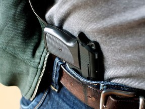 A handgun tucked into a mans waistband.