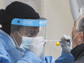 A health-care worker prepares to swab a man at a walk-in COVID-19 test clinic in Montreal North, Sunday, May 10, 2020, as the COVID-19 pandemic continues in Canada and around the world.