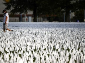 A person walks past the art installation "IN AMERICA How Could This Happen..." by artist Suzanne Brennan Firstenberg, as the spread of the coronavirus disease (COVID-19) continues, on the DC Armory Parade Ground, in Washington D.C., U.S., October 23, 2020.