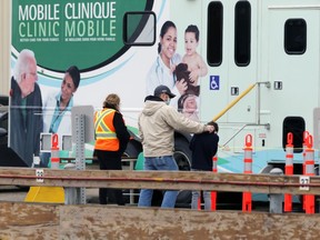 A man fixes the collar of a child as they wait to enter a mobile COVID-19 clinic set up in a parking lot next to 1181 Portage Avenue in Winnipeg on Wed., Sept. 30, 2020. Kevin King/Winnipeg Sun/Postmedia Network