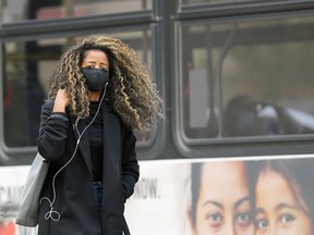 A woman wearing a mask walks on Main Street in Winnipeg on Thursday.