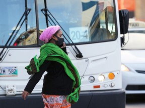 A woman wearing a mask crosses Main Street at McDermot Avenue in Winnipeg on Wed., Oct. 7, 2020. Kevin King/Winnipeg Sun/Postmedia Network