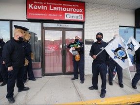 Justin Kelsch (centre) tries in vain to reach someone in the office of MP Kevin Lamoureux on Mandalay Drive during a federal union action in Winnipeg on Thurs., Oct. 8, 2020.  The Union of Canadian Correctional Officers has been without a contract since May 31, 2018 and is looking for a wage increase and more paid leave. Kevin King/Winnipeg Sun/Postmedia Network