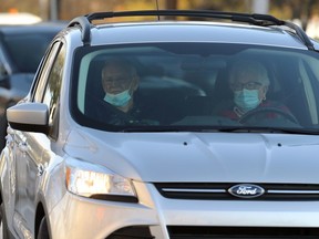 Two different approaches to mask-wearing in a car turning off Main Street onto Broadway in Winnipeg on Tues., Oct. 13, 2020. Kevin King/Winnipeg Sun/Postmedia Network